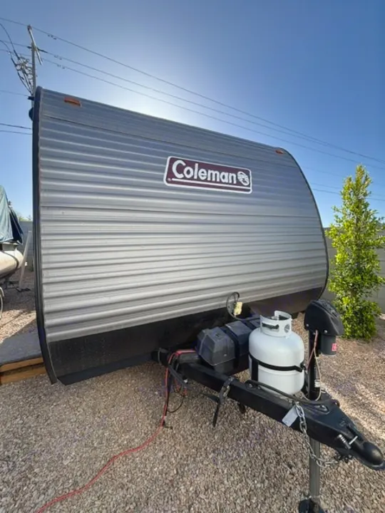 This grey Coleman travel trailer, equipped with a propane tank and hitch, is ready for your next RV rental adventure.. Dutchmen Coleman Lantern LT 2024