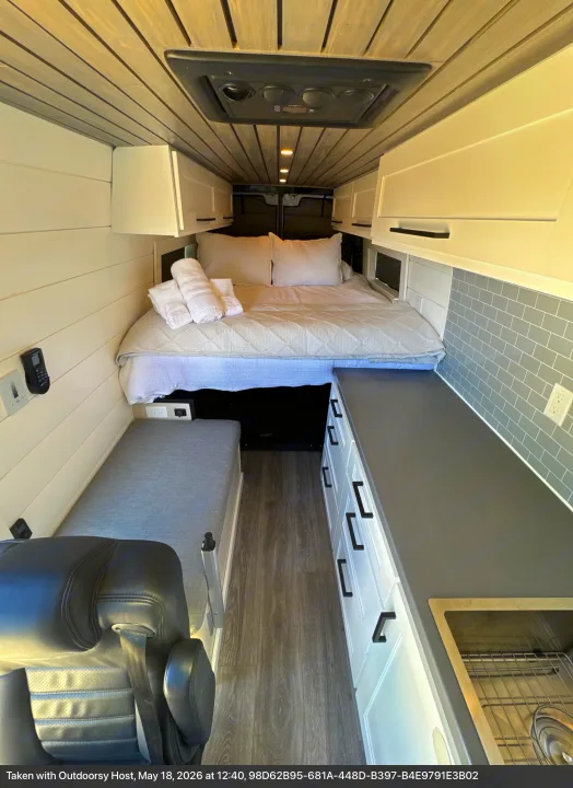Modern RV rental interior: a comfy bed, functional kitchen with sink, sleek cabinets, and cozy bench seating.. Mercedes-Benz Sprinter RV Motorhome Campervan 2012