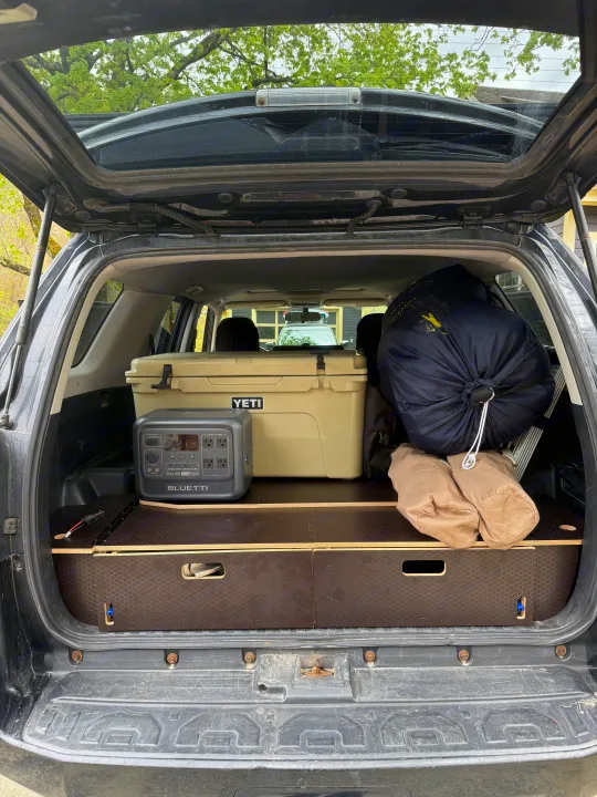 Car trunk setup with Yeti cooler, Bluetti power station, and camping gear, ideal for trips. Consider it for your next rv rental.. Toyota 4Runner 2014
