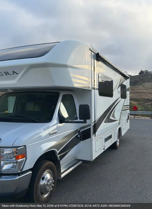 White Class C RV rental, an Integra Odyssey, parked by hills. Ready for your next outdoor adventure.. Entegra Coach Odyssey 2019