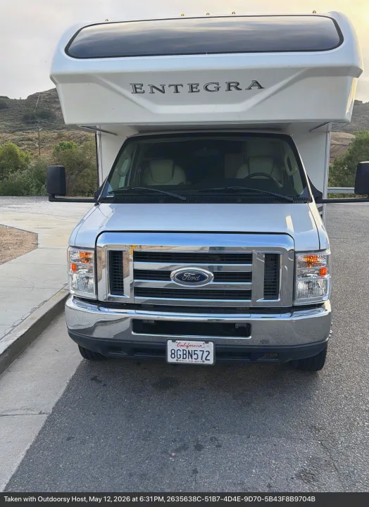 Front view of a white Entegra Class C rv rental, built on a Ford chassis, parked on asphalt on a sunny day.. Entegra Coach Odyssey 2019