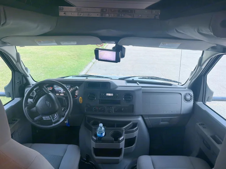 Inside a Ford E-Series rv rental van: driver's cockpit with dashboard, steering wheel, and backup camera display for travel.. Forester 2501CD 2023