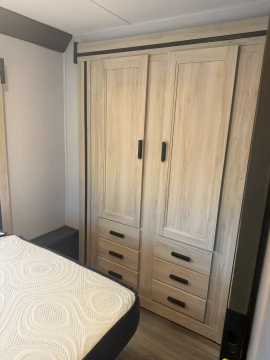 Inside an RV rental: a modern bedroom featuring a light wood wardrobe with multiple drawers and a white textured mattress.. Forester 2501CD 2023