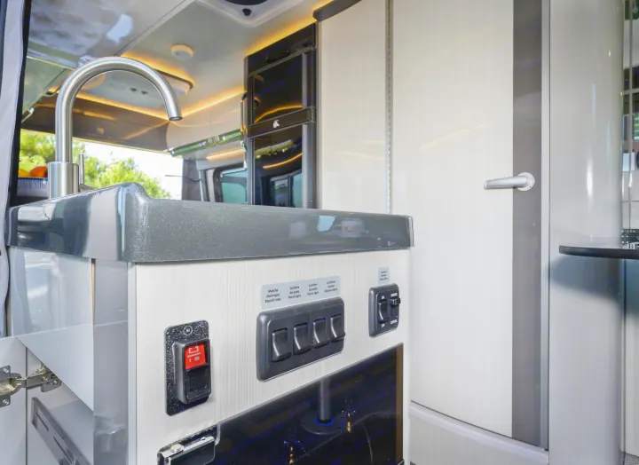 Modern RV rental kitchen with sink, faucet, and an illuminated control panel for electric step and various lights.. Other Gala Montecarlo 2025