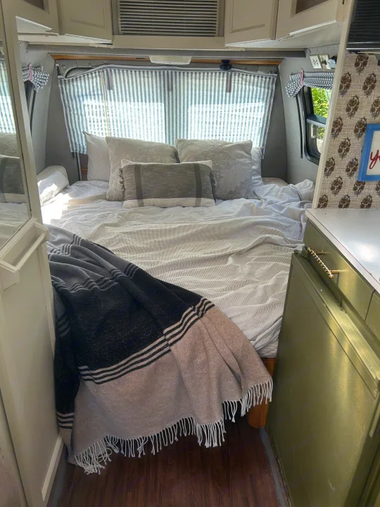 Cozy RV rental bedroom with striped bedding, fluffy pillows, and a comfy throw blanket, ideal for a relaxing getaway.. Roadtrek 190 Popular 1995