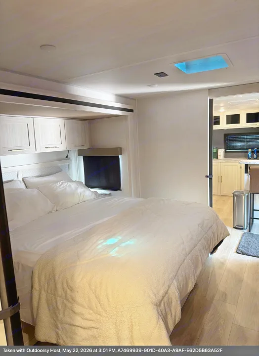 Cozy rv rental bedroom features a comfy bed, skylight, overhead cabinets, and a glimpse of the modern kitchen.. Forest River Surveyor Land Surveyor 2024