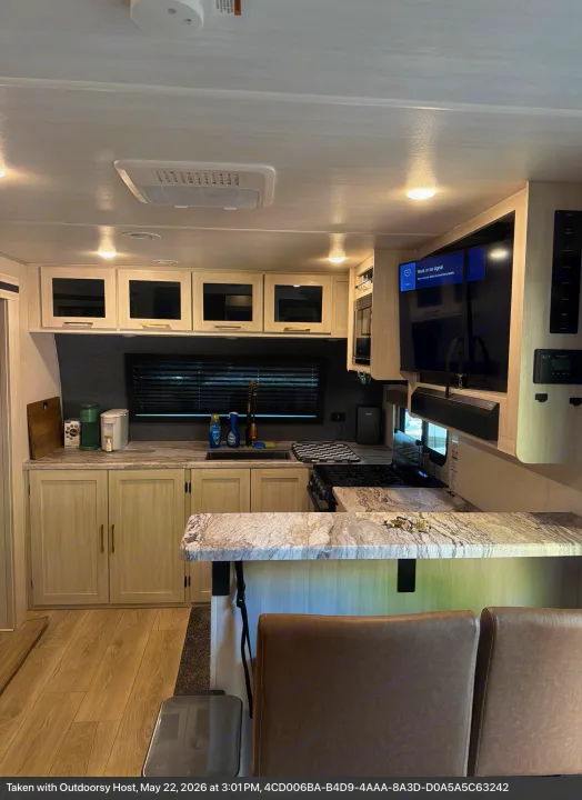 Modern RV rental kitchen & dining area: light wood cabinets, spacious counter, coffee maker, stove, and comfy chairs. Full amenities for your trip.. Forest River Surveyor Land Surveyor 2024