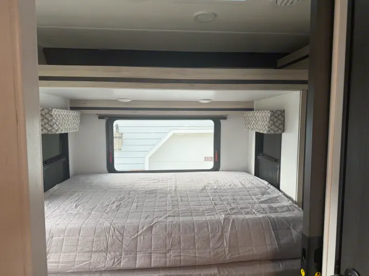 An RV rental bedroom features a spacious bed, natural light from the window, and modern finishes. Perfect for travel comfort.. Forester 2501CD 2023