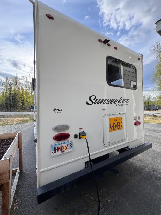 Rear of a white Sunseeker rv rental, plugged in with Alaska license plates "AHOMEK2" and "JHW 558" visible.. Forest River Sunseeker 2018