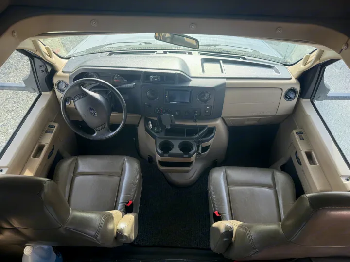 RV rental: full view of the front cabin, including the dashboard, Ford steering wheel, and both tan seats.. Forest River Sunseeker 2018