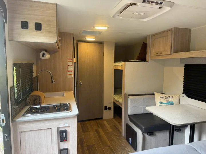 Step inside this rv rental: kitchenette with sink/stove, bunk beds, a dinette with seating/table, and overhead cabinets.. Heartland RVs Pioneer 2025