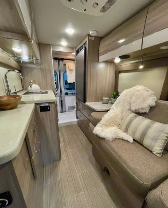 Explore this sleek RV rental: compact kitchen, comfy dinette with a plush throw, and modern amenities for your trip.. Thor Sequence 2022