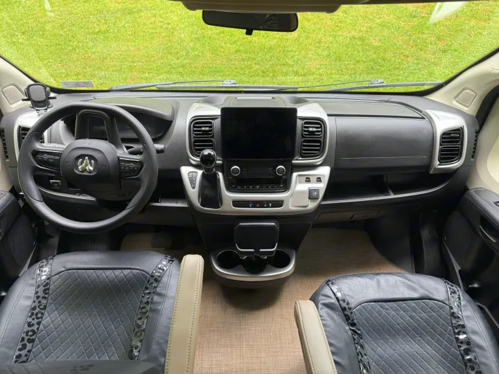 RV rental interior: clear view of the dashboard, Ram steering wheel, large infotainment screen, and detailed front seats.. Thor Sequence 2022