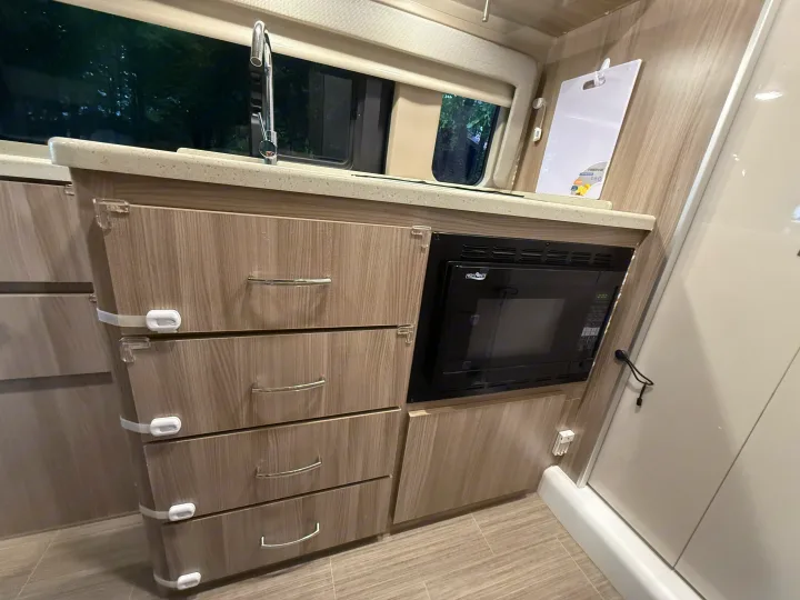 This rv rental features a compact kitchen with a sink, built-in microwave, and child-safe drawers for convenience.. Thor Sequence 2022