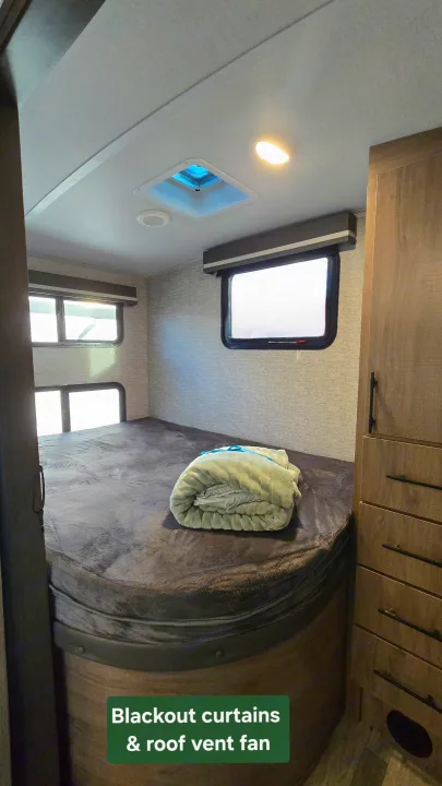 RV rental interior: A bedroom with a bed, blackout curtains, and roof vent fan for comfort.. Grand Design Imagine 2023