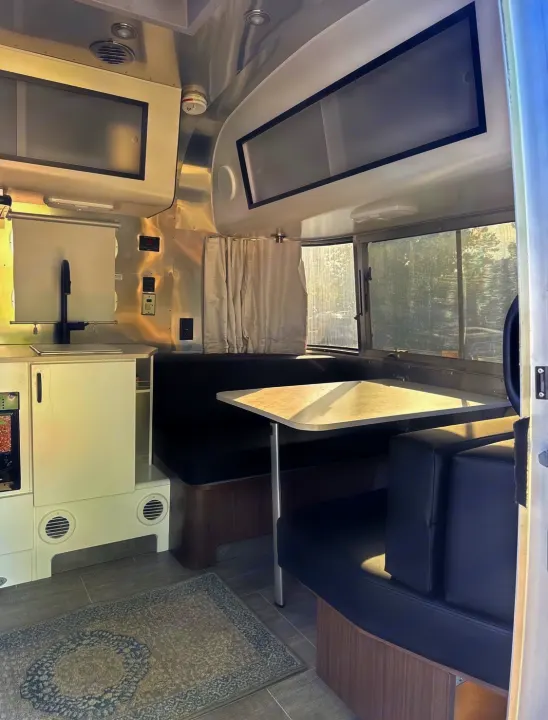 Modern rv rental interior with comfortable dinette, sleek kitchen, and overhead storage. Ideal for a cozy trip.. Airstream Caravel 2020