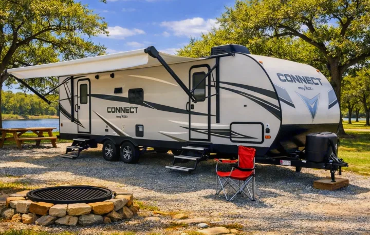 Enjoy an RV rental at a scenic lakeside campsite with a fire pit, picnic table, and extended awning for ultimate outdoor comfort.. Connect 261RL 2018