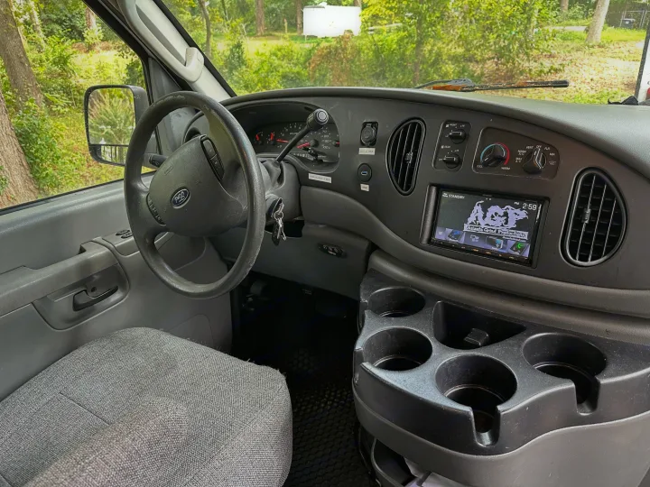 RV rental interior: Dashboard, steering wheel, radio, climate controls, & cupholders visible from the driver's seat.. Ford E250 Clubwagon 2007