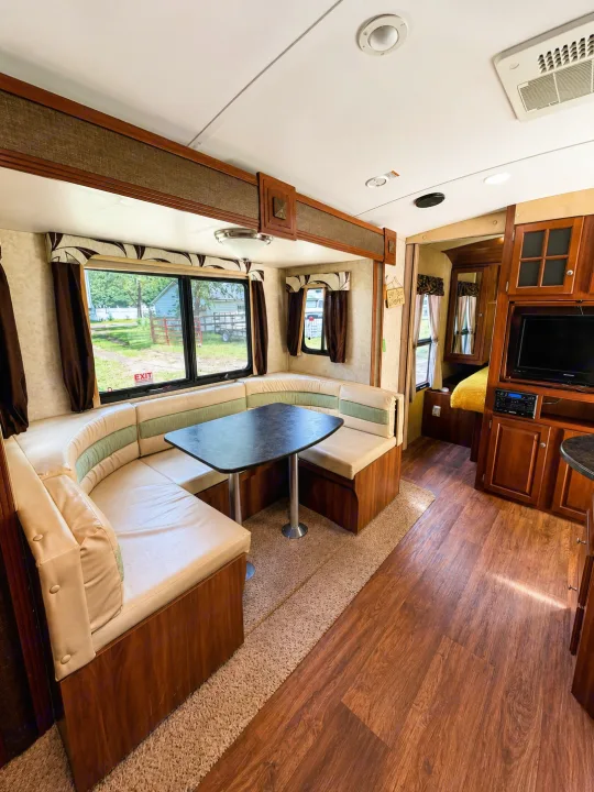 RV rental: Bright interior with curved dinette, wood floor, entertainment center, and windows with outdoor views.. Keystone RV Bullet Ultra Lite 2013