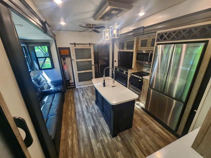 Inside a stylish RV rental: kitchen island, stainless appliances, living room recliners, and bunk area access.. Keystone RV Alpine Avalanche 2024