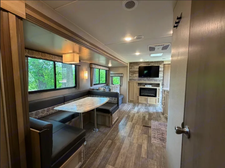 This RV rental's modern interior features a cozy dinette, bright windows, and a living area with TV & fireplace.. Coachmen Catalina Legacy 2022