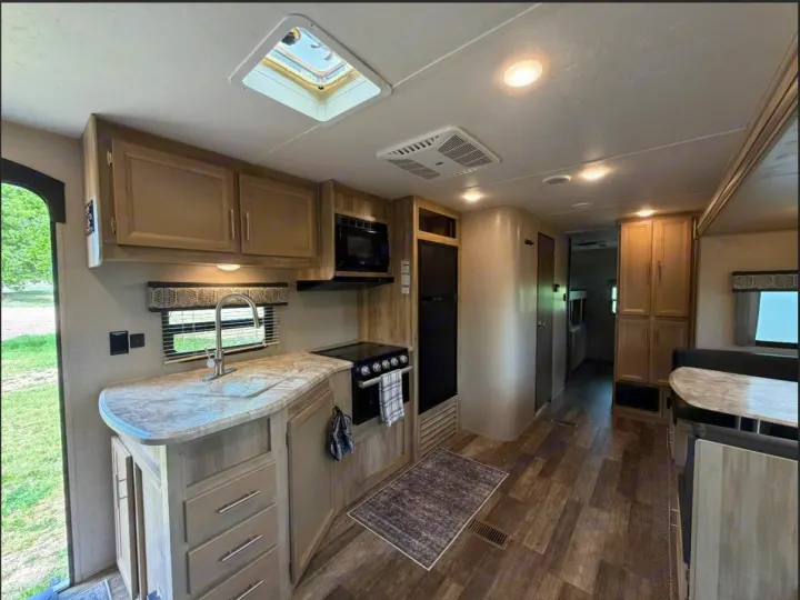 RV rental interior: well-equipped kitchen with sink, stove, microwave, fridge, and cabinets, plus a dinette dining area.. Coachmen Catalina Legacy 2022