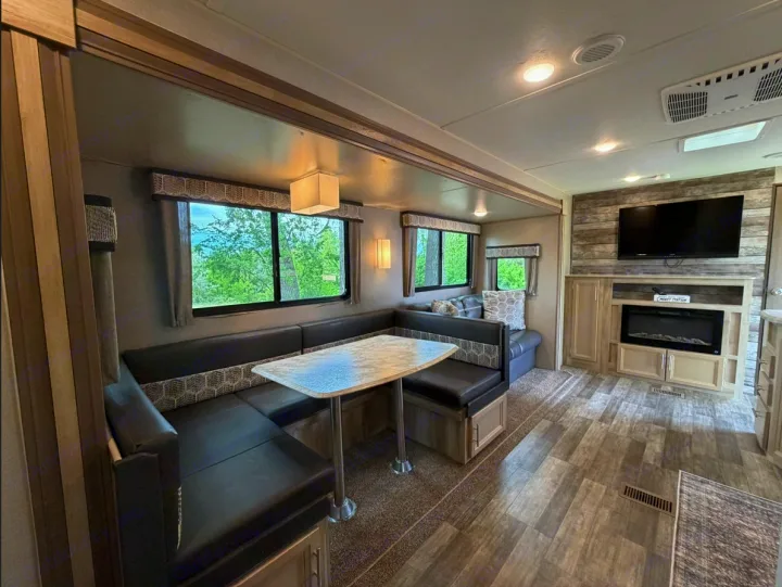Spacious RV rental interior: a comfy U-shaped dinette, dining table, and living area with a TV & fireplace for relaxation.. Coachmen Catalina Legacy 2022