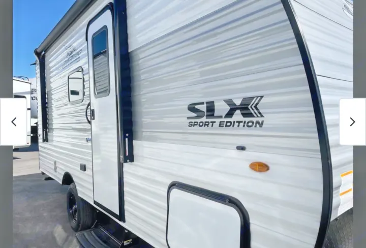 This RV rental shows the sleek side of a white and gray Jayco SLX Sport Edition travel trailer, with stripes, a door, and awning.. Jayco Jayco 2026