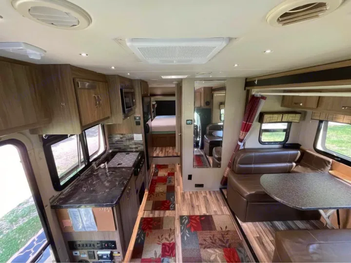 View of a modern rv rental's interior, featuring a well-equipped kitchen, comfortable dinette, and a rear bedroom.. Isata 3 2017