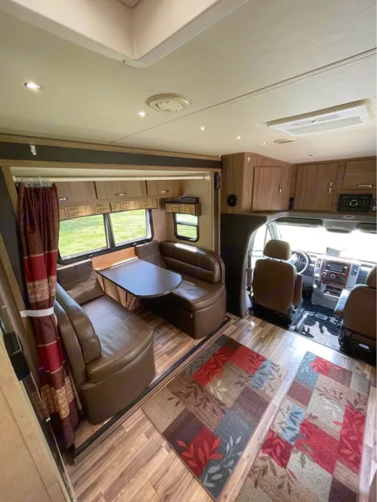 Spacious RV rental interior: large dinette, wood floors, colorful rugs, and driver's area. Ready for your road trip adventures!. Isata 3 2017