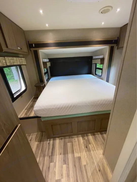 Spacious RV rental bedroom featuring a queen bed in a slide-out, wood-look floor, and windows. Ready for your trip.. Isata 3 2017