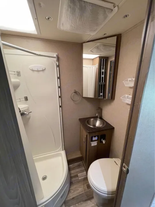 Compact RV rental bathroom featuring a corner shower, sink with mirror, and toilet, ideal for travel.. Isata 3 2017
