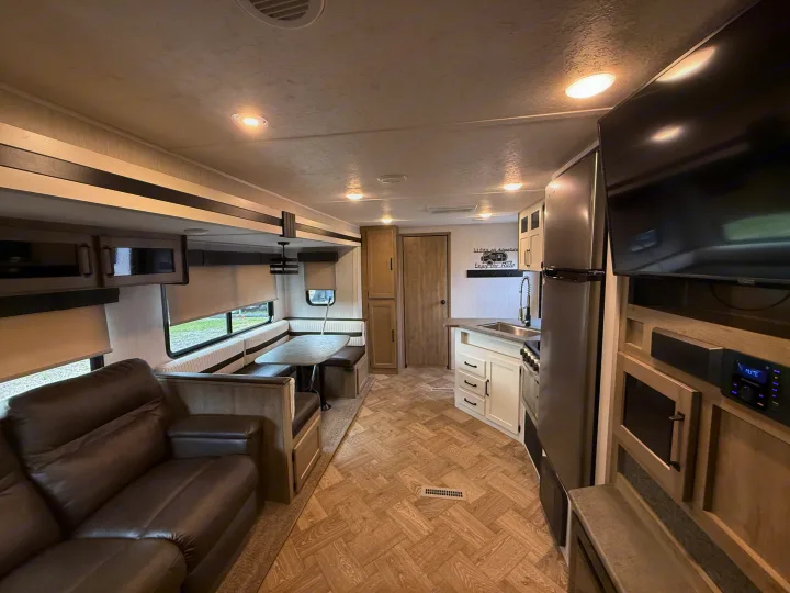 Spacious RV rental interior featuring a comfy sofa, dinette, full kitchen, and entertainment center with modern decor.. Forest River Palomino Puma 2022