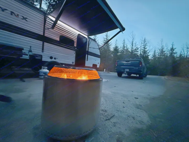 Cozy RV rental evening: fire pit illuminates camper and pickup under a blue dusk sky at a serene campsite.. Heartland RVs Prowler Lynx 2024