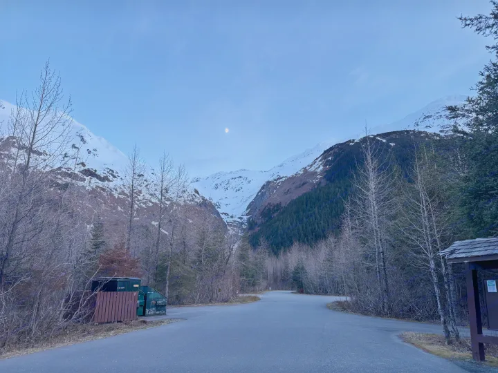 A tranquil mountain valley at dusk, with snow-capped peaks, bare trees, and a winding road under the moon. Ideal for an RV rental trip.. Heartland RVs Prowler Lynx 2024