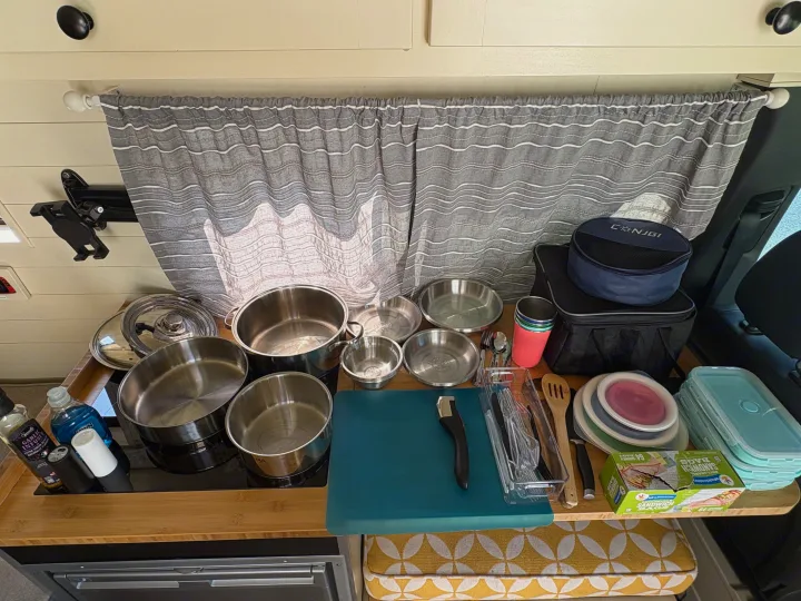 An RV rental's organized kitchen counter with compact pots, pans, collapsible bowls, and other cooking essentials.. Mercedes-Benz Sprinter 2020