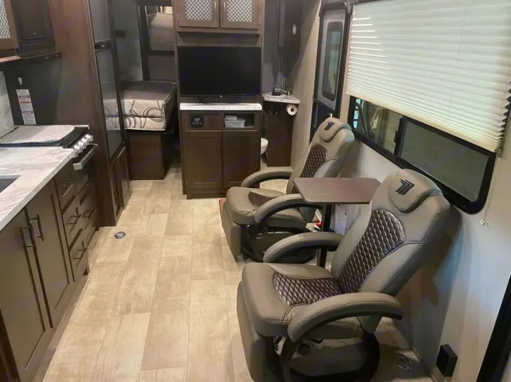 Spacious RV rental interior: kitchen, comfy recliners, entertainment, and a glimpse of a sleeping area. Ideal for travel.. Grand Design Momentum 2021