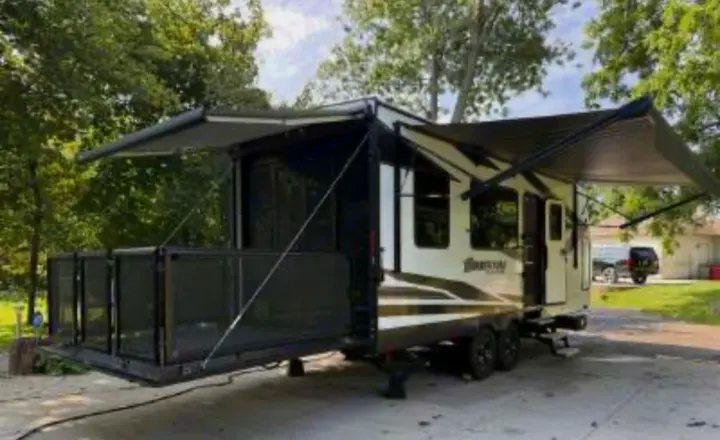 This spacious RV rental, a toy hauler with a rear deck and extended awnings, is parked outdoors, ready for adventure.. Grand Design Momentum 2021