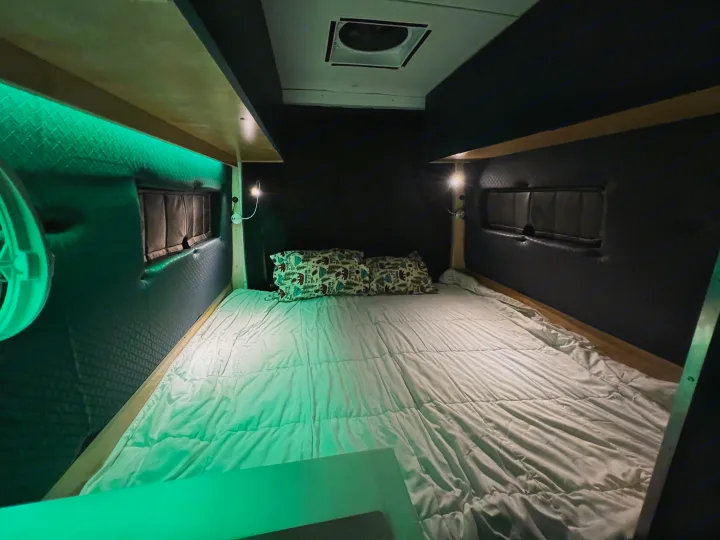 Cozy RV rental bed area featuring green LED accent lighting, individual reading lights, and nature-themed pillows.. Mercedes-Benz Sprinter 2023