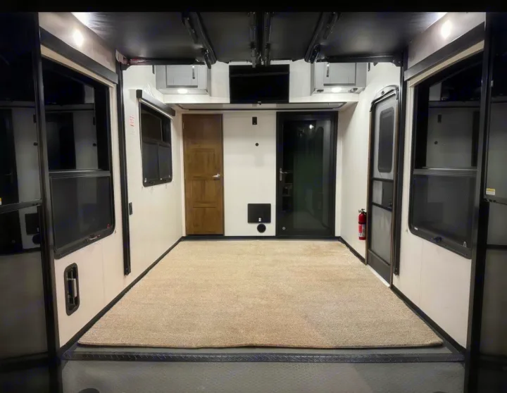 This rv rental features a clean, carpeted garage area, ideal for gear. Windows, doors & overhead storage visible.. Keystone Fuzion 2020