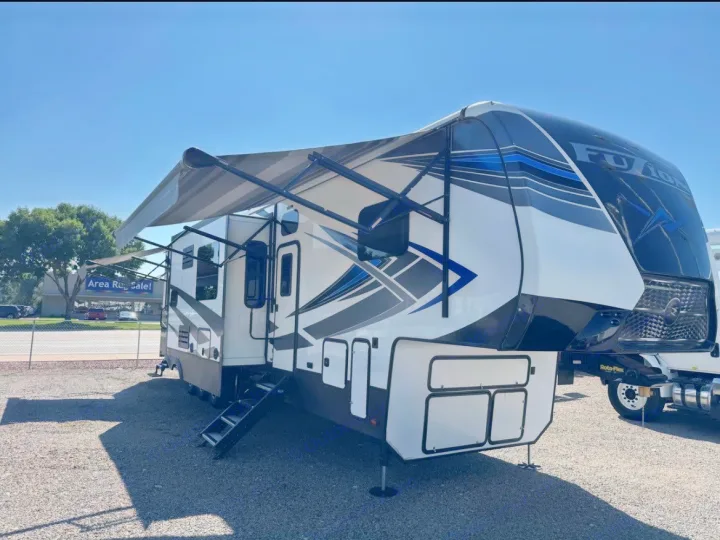Modern white and blue Fuzion fifth-wheel RV rental, awnings out and steps down, ready for your next adventure.. Keystone Fuzion 2020