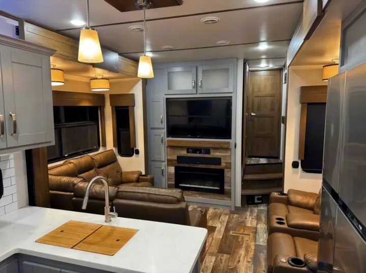 Modern rv rental living area features comfy recliners, TV, fireplace, and a kitchen counter. Bright & inviting interior.. Keystone Fuzion 2020