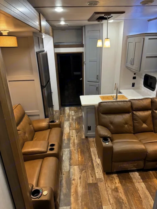 An inviting RV rental interior with plush leather seating, a modern kitchen, bunk beds, and wood-look flooring.. Keystone Fuzion 2020