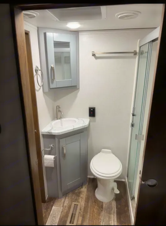 Compact RV rental bathroom with corner sink, toilet, and shower. Ideal for travel and camping comfort.. Keystone Fuzion 2020