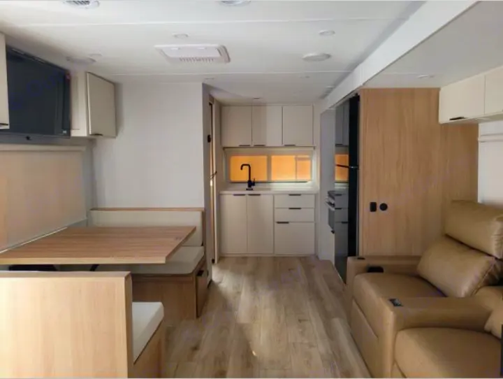 Modern RV rental interior showing a clean kitchen, dinette with TV, and comfortable living room seating.. Winnebago Thrive 2026