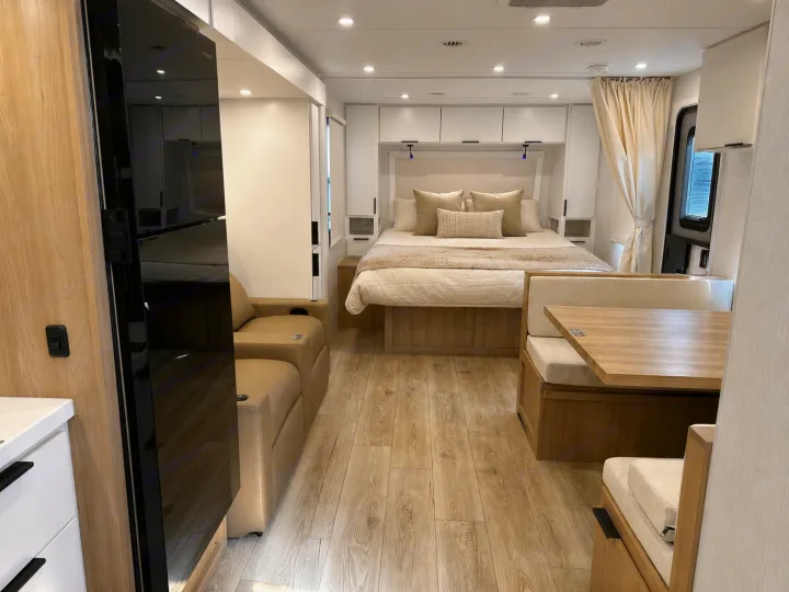 Spacious RV rental interior featuring a modern bedroom, dinette, and sofa. Bright, comfortable, and ready for adventure.. Winnebago Thrive 2026