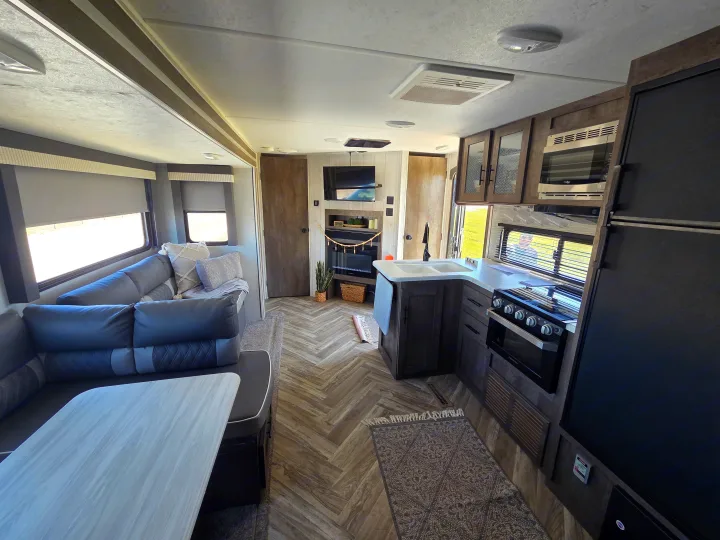 Spacious & modern rv rental interior with kitchen, living area, and fireplace. Perfect for your next adventure!. Forest River Wildwood 2021