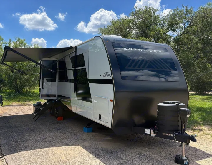 Sleek black & white Brinkley rv rental travel trailer parked with awning extended, ready for a sunny adventure.. Brinkley RV Model I 2025