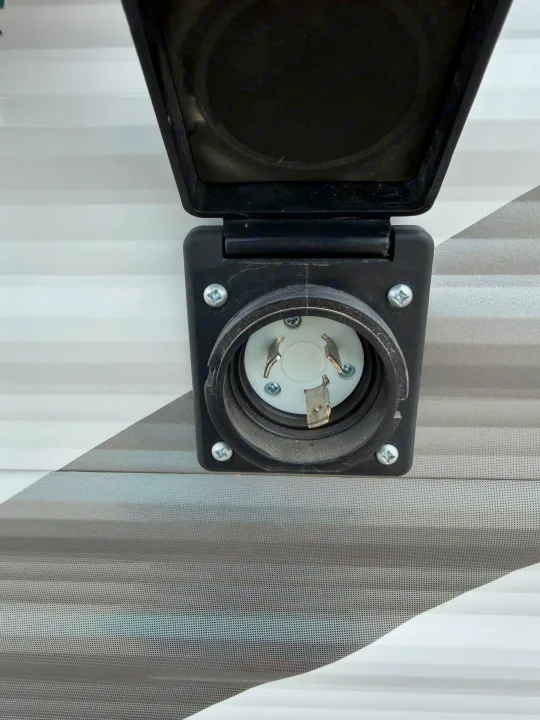 Close-up of a 30 Amp twist-lock shore power inlet on an RV rental, essential for connecting to campsite electricity.. Highland Ridge RV Open Range 2023