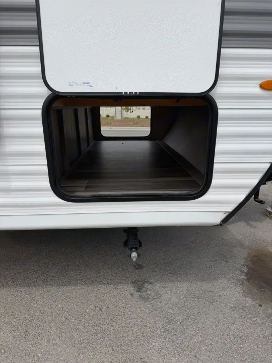 Open pass-through storage on an RV rental, ideal for packing gear. A stabilizer jack is visible below the compartment.. Highland Ridge RV Open Range 2023